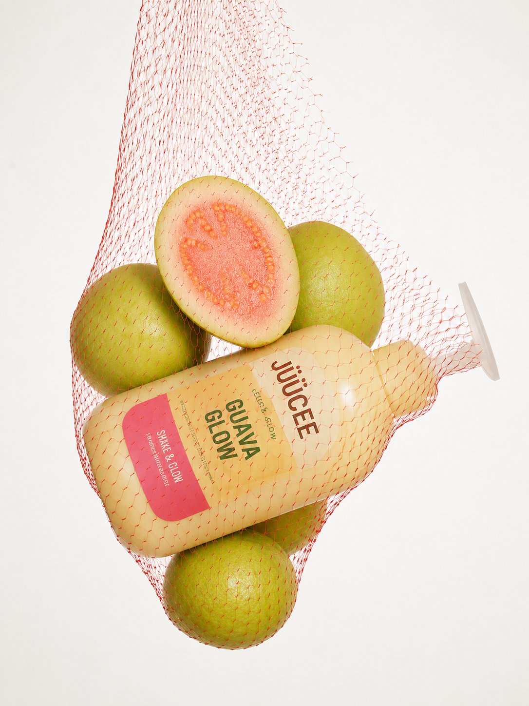 Red mesh bag guavas with juice bottle product shot