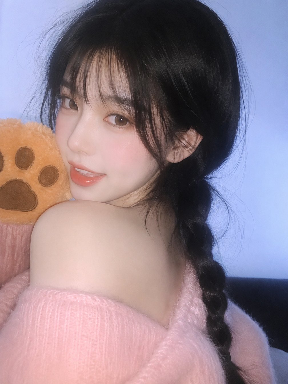 young woman with black bangs in pink sweater holding