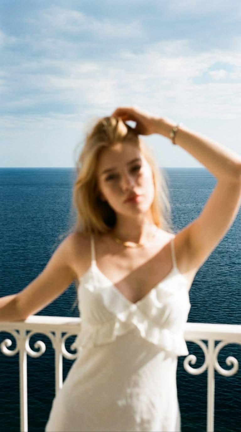 Blurred woman in white dress on sea balcony