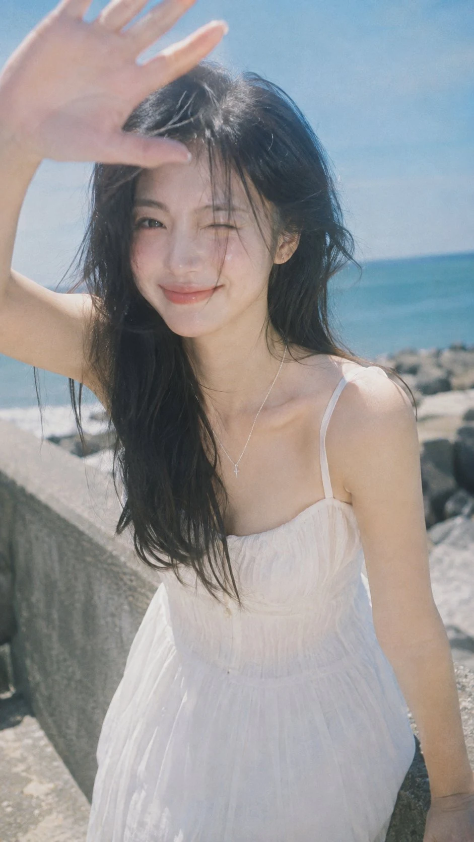 young woman winking at seaside with hand shielding