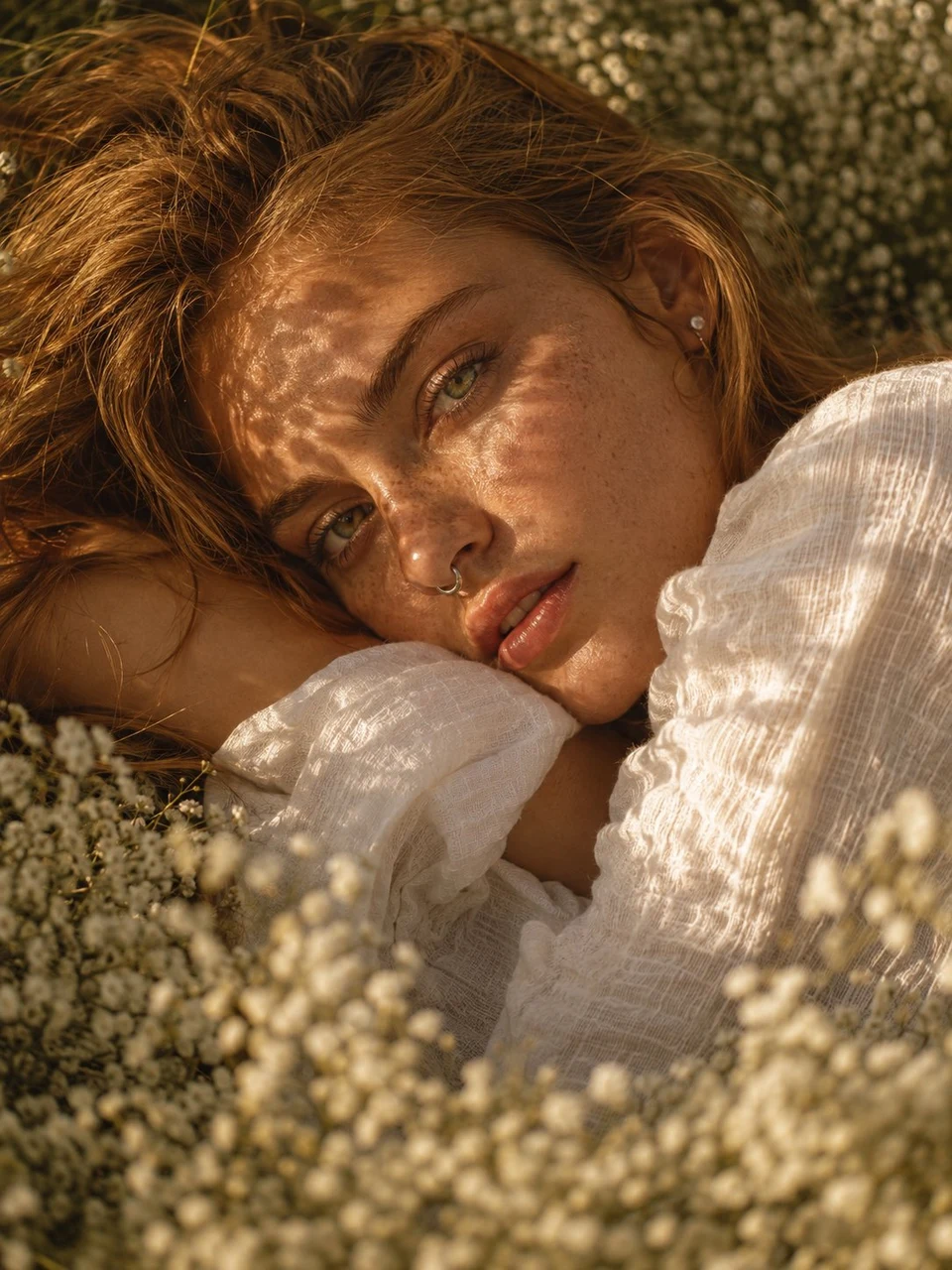 Freckled woman lying in baby's breath field