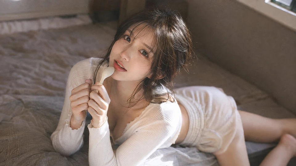 Korean woman in white knit loungewear lying on bed