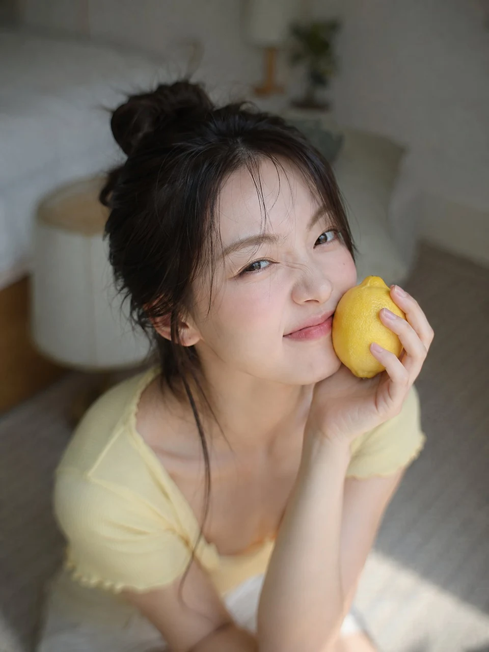 Korean woman holding lemon in bedroom portrait
