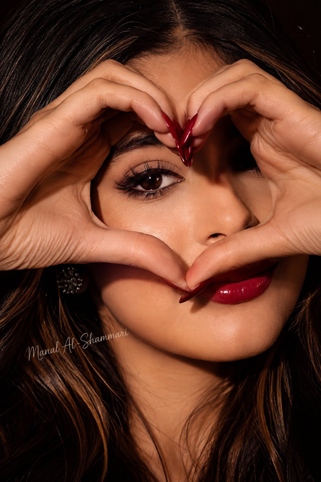 Woman framing eye with heart-shaped hands