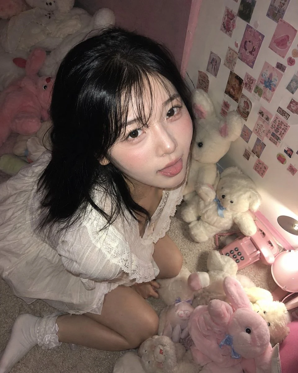 Young woman posing among pink and white plush toys