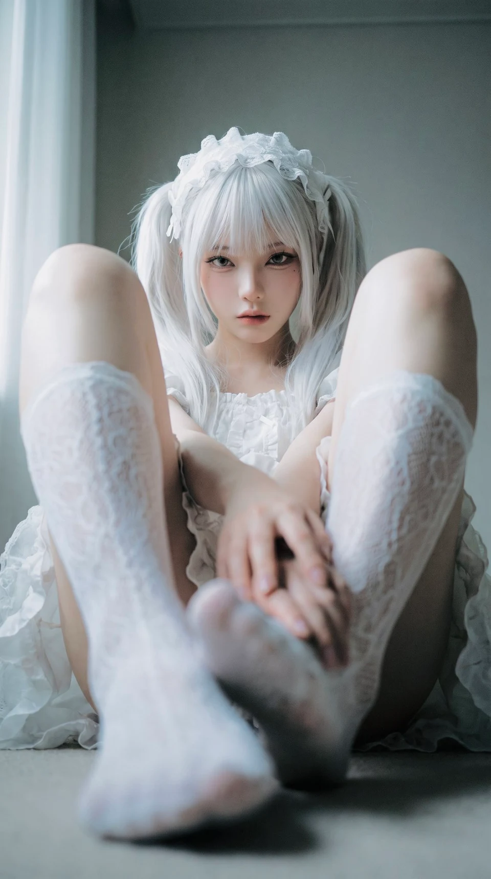 Two identical twin sisters in white lace sitting on