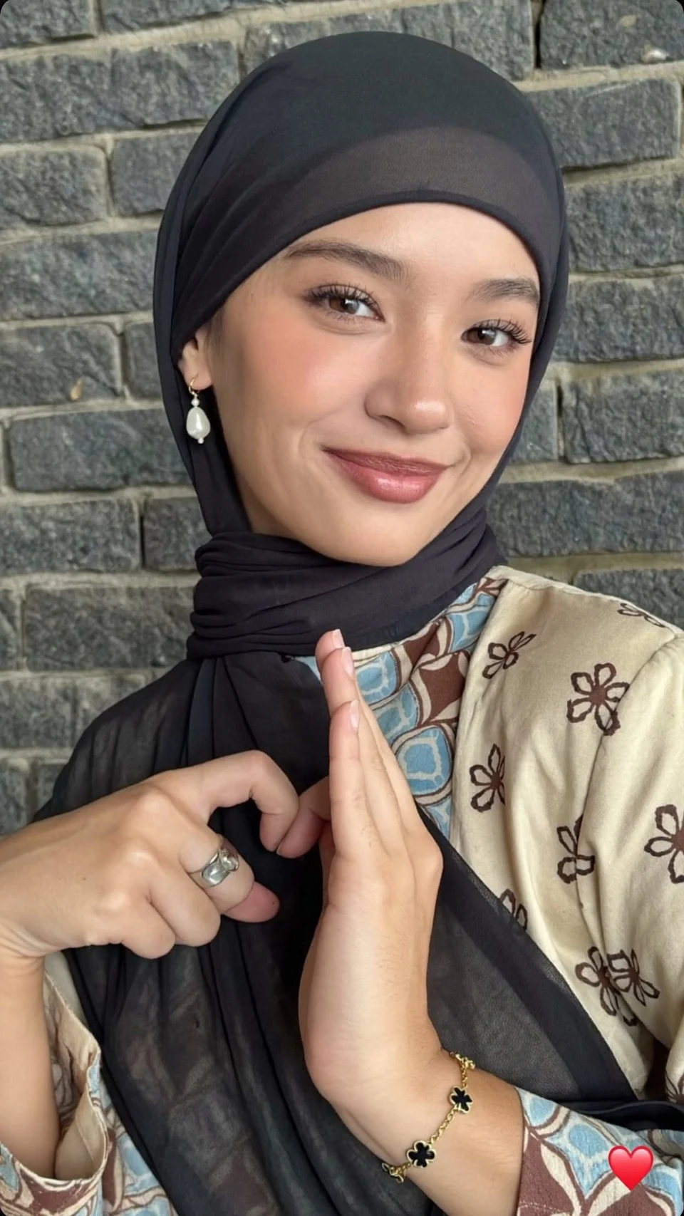 hijabi woman making heart hands gesture