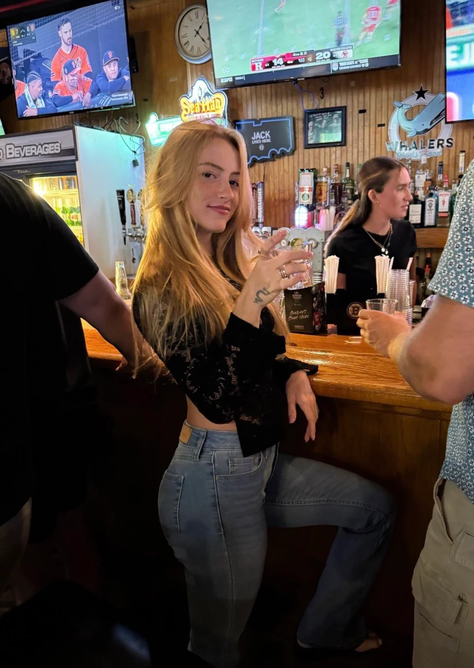 Blonde woman at wooden bar holding drink