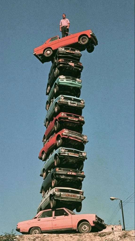 Vintage Car Stack Art Installation With Man on Top